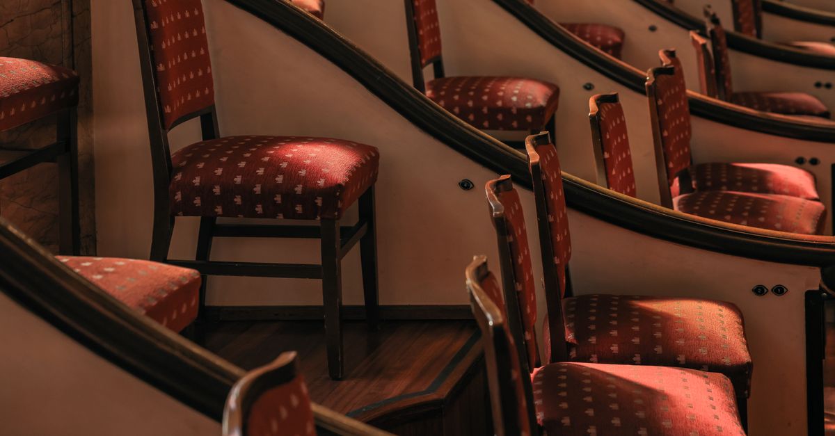 Curved rows of elegant red theater seats in a sunlit Barcelona auditorium.